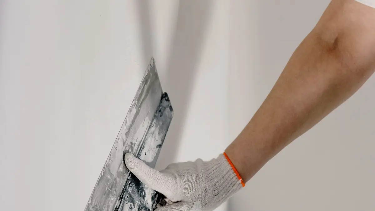 A drywall patch being smoothed with a knife